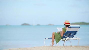 jovem lendo livro durante a praia branca tropical video