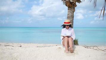 Young woman reading book during tropical white beach video