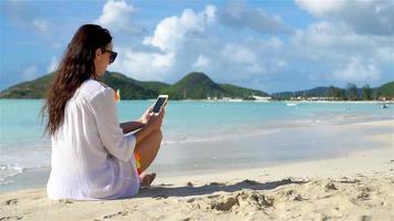 giovane donna con Telefono su tropicale spiaggia. bellissimo ragazza su il spiaggia con cellulare su caraibico isola video