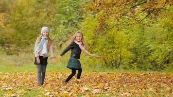 poco adorabile ragazze avendo divertimento con le foglie a caldo giorno nel autunno parco all'aperto video