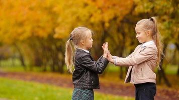 Little adorable girls having fun at warm day in autumn park outdoors video