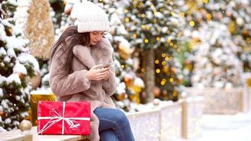 linda mulher está lendo mensagem de texto no celular enquanto está sentado no parque. video