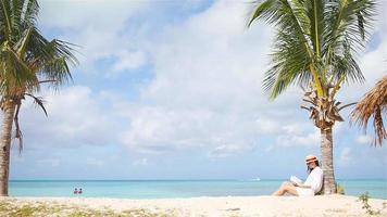 jeune femme lisant un livre pendant une plage blanche tropicale video
