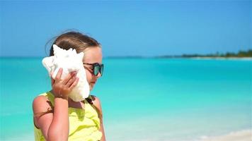 Portrait of little cute girl with a big seashell background the sea