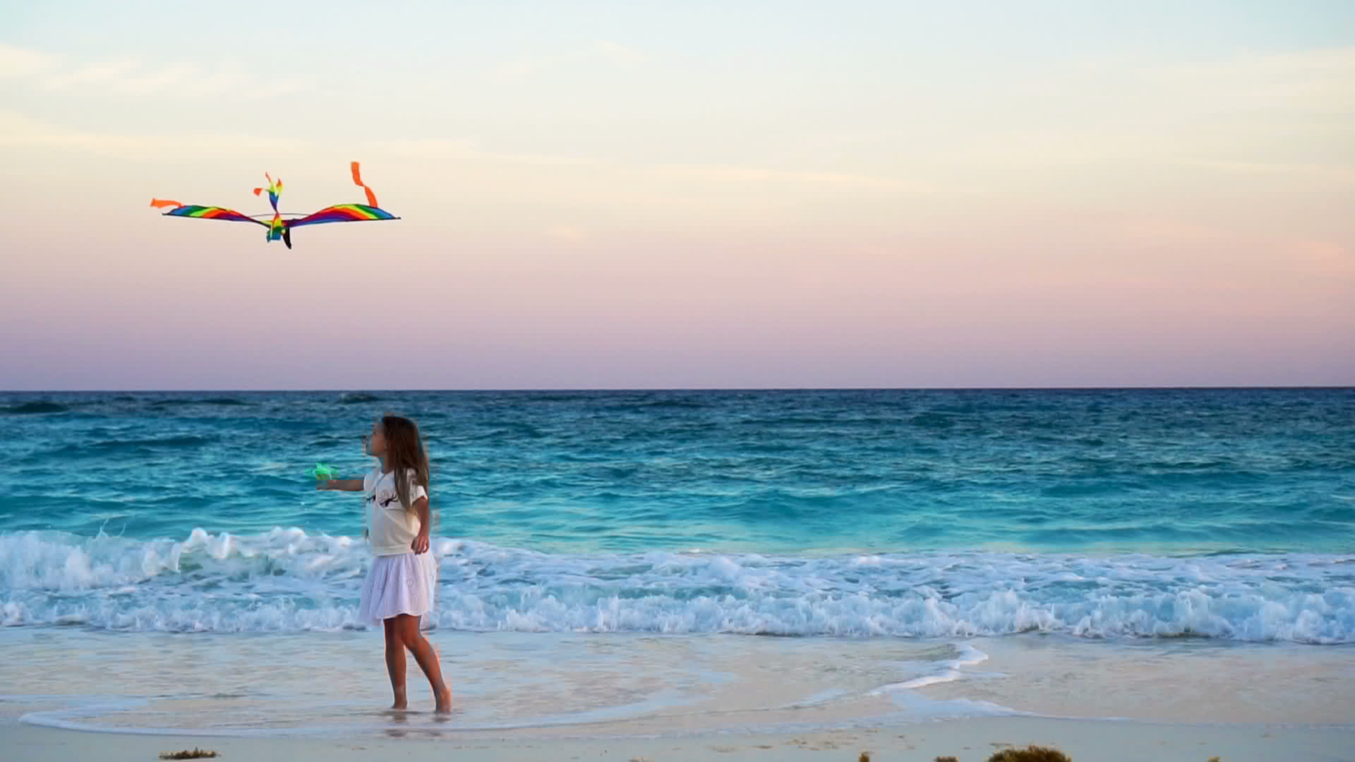 Adorable little girl with flying kite on tropical beach. Kid play on