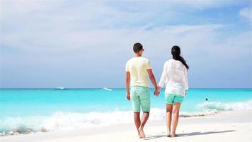 joven pareja en playa blanca durante las vacaciones de verano. amantes felices disfrutan de su luna de miel. vídeo en cámara lenta. video