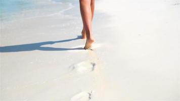 piernas femeninas corriendo por la playa blanca en aguas poco profundas. concepto de vacaciones en la playa y descalzo. camara lenta. video