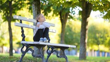 süßes Kind sitzt gedankenverloren am schönen Herbsttag im Freien. kleines Mädchen auf der Bank im Herbst