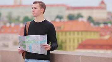 hombre turista con mapa de la ciudad y mochila en europa. niño caucásico mirando con mapa de ciudad europea en busca de atracciones. video