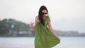 mujer hermosa joven en la costa tropical. chica turista vestida de verde en la playa