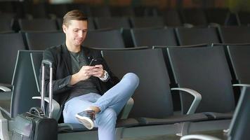 stedelijk bedrijf Mens pratend Aan slim telefoon op reis binnen in luchthaven. gewoontjes jong zakenman vervelend pak jasje. jong Mens met mobiele telefoon Bij de luchthaven terwijl aan het wachten voor instappen.