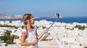 Adorable little girl taking selfie photo background Mykonos town in Greece