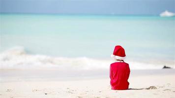 Little adorable girl in Christmas hat on white beach during Xmas vacation video