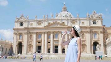 mujer joven bebiendo agua en un día caluroso de fondo en st. basílica de san pedro en ciudad del vaticano, roma, italia. video