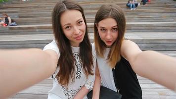 Lifestyle selfie portrait of two young positive woman having fun and making selfie. Concept of friendship and fun with new trends and technology. Best friends saving the moment with modern smartphone video