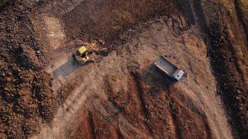 Aerial view of a wheel loader excavator with a backhoe loading sand into a heavy earthmover at a construction site. Excavator digging soil pits for the agricultural industry. video