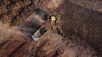 vue aérienne d'une pelle chargeuse sur pneus avec une rétrocaveuse chargeant du sable dans un engin de terrassement lourd sur un chantier de construction. excavatrice creusant des fosses de sol pour l'industrie agricole. video
