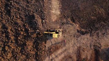 excavatrice creuser le sol sur le chantier de construction. vue aérienne d'une pelle chargeuse sur pneus avec une chargeuse-pelleteuse chargeant du sable dans un engin de terrassement lourd. excavatrice creusant des fosses de sol pour l'industrie agricole. video