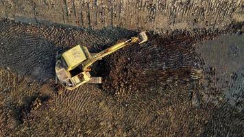 Excavator dig ground at construction site. Aerial view of a wheel loader excavator with a backhoe loading sand into a heavy earthmover. Excavator digging soil pits for the agricultural industry. video