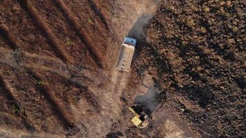 antenne visie van een wiel lader graafmachine met een backhoe bezig met laden zand in een zwaar grondverzetmachine Bij een bouw plaats. graafmachine graven bodem kuilen voor de agrarisch industrie. video