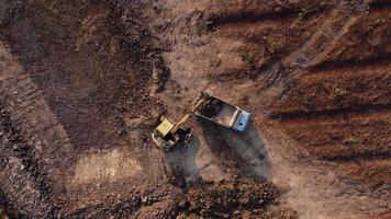 vue aérienne d'une pelle chargeuse sur pneus avec une rétrocaveuse chargeant du sable dans un engin de terrassement lourd sur un chantier de construction. excavatrice creusant des fosses de sol pour l'industrie agricole. video