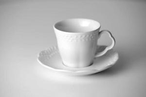 White tea cup and saucer with a pattern for drink on white background. Ceramic coffee cup or mug close up. Mockup classic porcelain utensils. copy space photo