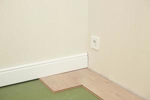 Installing wooden laminate or parquet floor in room over green base. assembling panels quickly and easily - affordable flooring. laying laminate flooring at home photo