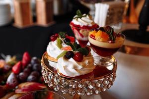 luxury wedding catering, table with modern desserts, cupcakes, sweets with fruits. delicious candy bar at expensive wedding reception. party holiday celebration. selective focus photo