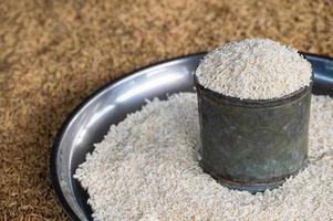 White rice containing in metal can on a tray with paddy rice on the background. Rice is a staple crop for much of the world's population. photo