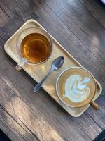 Cup of Hot Coffee with Picture on Foam Closeup. Pot with Aroma Morning Drink Espresso on Saucer and Beans on Brown Wooden Background Table. Fresh Energy Aromatic Barista Breakfast Beverage photo