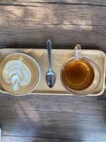 Cup of Hot Coffee with Picture on Foam Closeup. Pot with Aroma Morning Drink Espresso on Saucer and Beans on Brown Wooden Background Table. Fresh Energy Aromatic Barista Breakfast Beverage photo