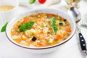 Minestrone, italian vegetable soup with pasta on white table. Vegan soup. photo