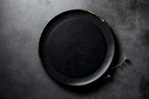 Black plate on stone table top view. Empty space for menu or recipe. photo