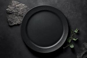 Black plate on stone table top view. Empty space for menu or recipe. photo