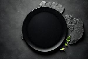 Black plate on stone table top view. Empty space for menu or recipe. photo