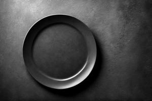 Black plate on stone table top view. Empty space for menu or recipe. photo