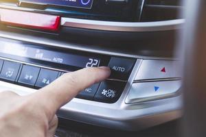 conductor presionando el botón de enfriamiento automático del aire acondicionado del automóvil