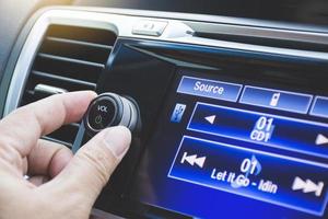 controlador girando el botón de ajuste de volumen de la radio del coche en el interior de la consola del coche