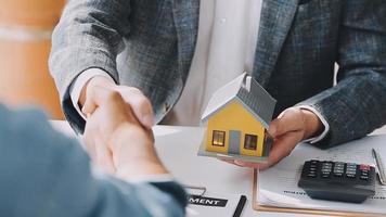 agente de corretaje de bienes raíces entrega una muestra de una casa modelo al cliente, contrato de préstamo hipotecario que arrienda y compra y vende casa y contrata el concepto de préstamo hipotecario de seguro de hogar video