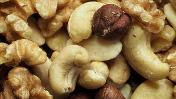 Mix of tasty nuts on a wooden surface. Cashews, almonds, hazelnuts and walnuts. video