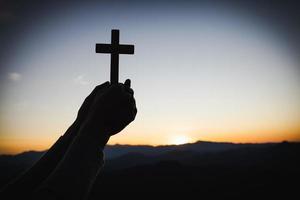 silueta de mujer cristiana rezando a mano, mujer sosteniendo un crucifijo rezando, espiritualidad y religión, mujer rezando a dios. concepto de cristianismo. foto