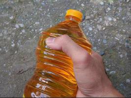 mano masculina sosteniendo una botella de aceite de cocina foto