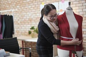 la diseñadora de vestuario asiática madura mide el tamaño de la forma de la marioneta de vestir en un estudio y trabaja con ropa, colección de diseño de moda, sastre boutique profesional, modista pyme emprendedora. foto