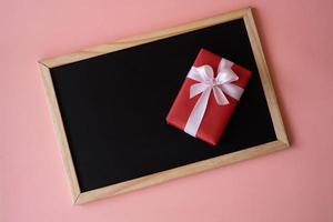 Red gift box on the black board isolated on pink background. photo