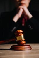 Justice and law concept.Male judge in a courtroom with the gavel, working with, computer and docking keyboard, eyeglasses, on table in morning light photo