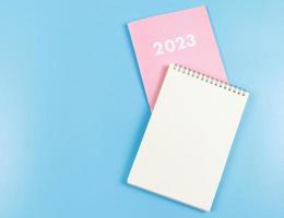 flat lay of blank paper note book on pink diary 2023 on blue  background. photo