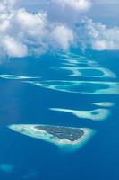 vista aérea de los arrecifes de coral en las islas maldivas. paisaje aéreo tropical. vacaciones de verano de lujo y destino de viaje foto