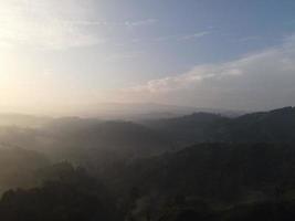 Aerial view of foggy forest landscape in Indonesia at sunrise. photo