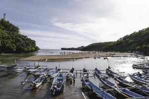 Baron Beach in Gunung Kidul, Indonesia with visitor and traditional boat. Yogyakarta, Indonesia - January, 2023. photo