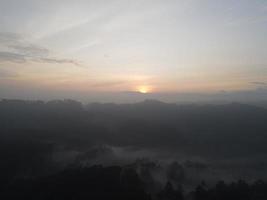 Aerial view of foggy forest landscape in Indonesia at sunrise. photo